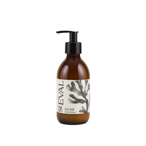 An amber glass pump bottle of Seval Sea Salt Hand Lotion with a black pump dispenser and a white label featuring a black coral illustration.