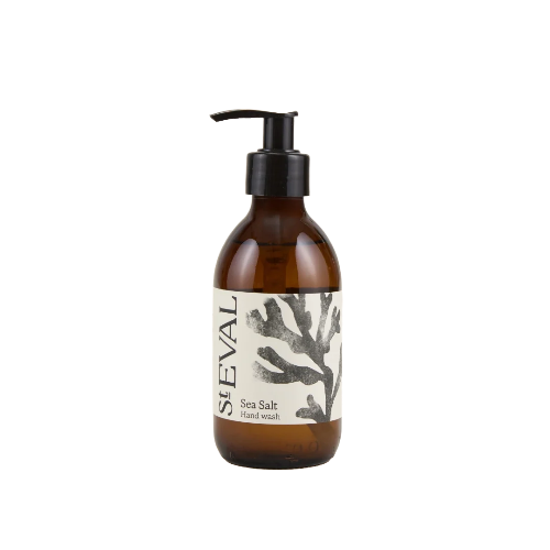 An amber glass pump bottle of StEVAL Sea Salt Hand wash with a black pump dispenser and a cream label featuring a black coral illustration, isolated on a white background.