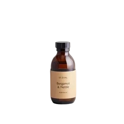 An amber glass bottle of SE EVAL Bergamot & Nettle Soaked Oil with a beige label and black cap, centered on a solid white background.