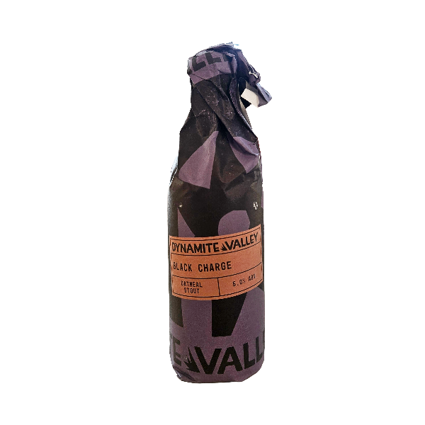 A single bottle of Dynamite Valley Black Charge oatmeal stout, wrapped in a dark purple and black patterned paper sleeve, isolated on a white background.