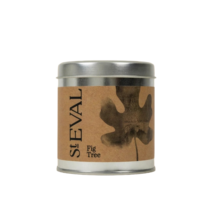 A round metal tin candle with a kraft paper label featuring a dark brown fig tree leaf and the text 'SEVAL Fig Tree'.
