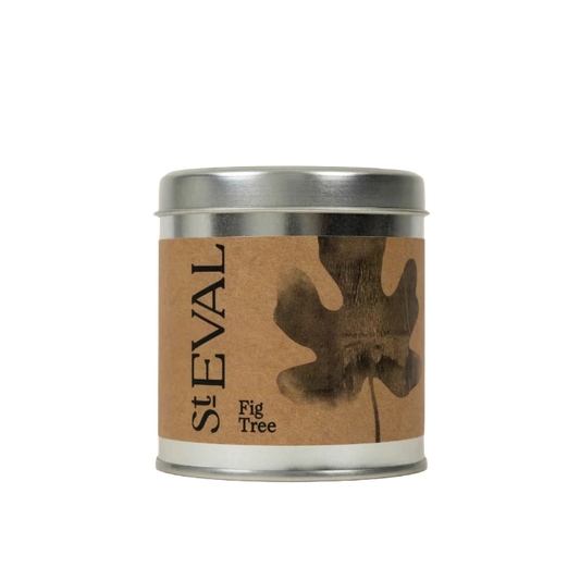 A round metal tin candle with a kraft paper label featuring a dark brown fig tree leaf and the text 'SEVAL Fig Tree'.
