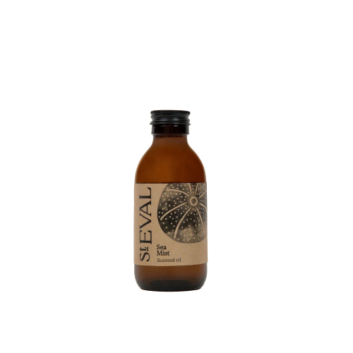 A small amber glass bottle of St Eval Sea Mist Scented Oil with a black screw cap and a brown paper label featuring a sea urchin design, centered on a plain white background.