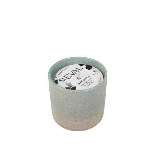 A ceramic candle in a speckled light blue and beige pot with a white wax top and a circular label that reads 'SHEVAL' and 'MAYA CANDLE'.